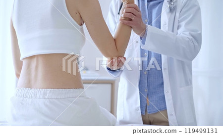 Doctor man examines a patient's elbow during a medical consultat 119499131