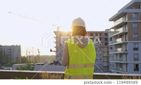 Construction female engineer taking notes and writing on clipboard while inspecting a building site at sunset Construction female engineer taking notes and writing on clipboard while inspecting a building site at sunset 119499389