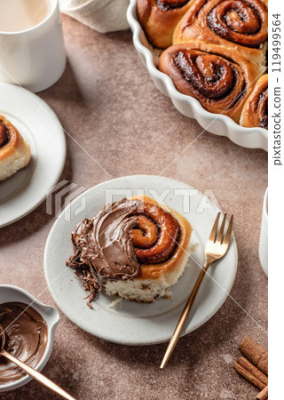 Chocolate swirl buns with hazelnut chocolate filling. Chocolate cinnamon buns and coffee served for breakfast on brown background 119499564