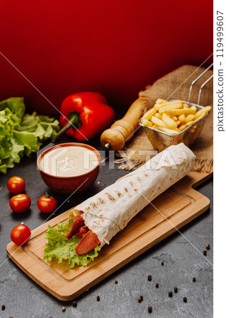 Grilled sausage wrap with fresh lettuce, a perfect quick snack or meal for on-the-go moments 119499607