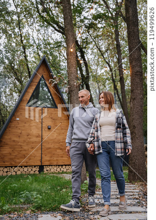 Romantic walk through nature near a cozy wooden cabin, capturing the charm of outdoor getaways Romantic walk through nature near a cozy wooden cabin, capturing the charm of outdoor getaways 119499626