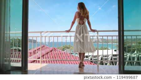 Beautiful happy woman in long dress enjoy ocean view from balcony window door terrace. Female relax, Phuket, Thailand exotic nature. Outdoor lifestyle travel summer holiday vacation on tropical island 119499687