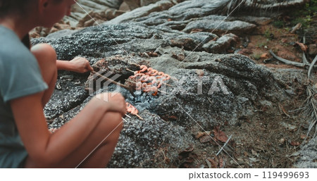 Woman making seafood barbeque sit on rocks on sea cost. Evening time, dark toning. Cooking shrimps on open fire. Leisure, food, people. Outdoor lifestyle travel summer holiday vacation. Slow Woman making seafood barbeque sit on rocks on sea cost. Evening time, dark toning. Cooking shrimps on open fire. Leisure, food, people. Outdoor lifestyle travel summer holiday vacation. Slow 119499693