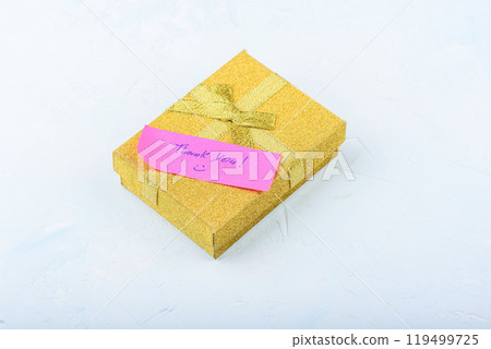 Yellow gift box with ribbon and pink stationery with handwritten inscription Thank you. 119499725