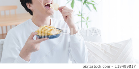 Smiling man eating potato chips Smiling man eating potato chips 119499817