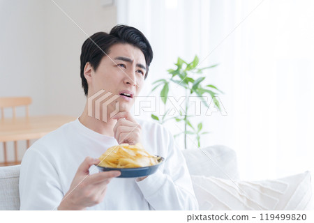 A man wondering whether to eat potato chips (potato chips, diet, gain weight, unhealthy) 119499820