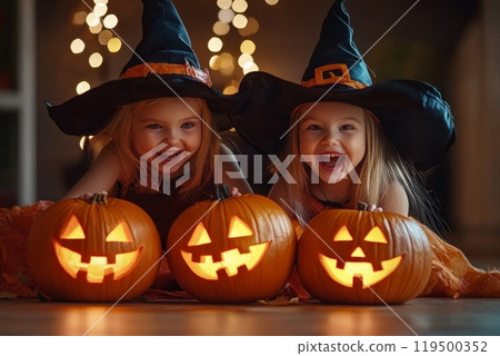 Two little girls wearing witch costumes posing with pumpkins for halloween Two little girls wearing witch costumes posing with pumpkins for halloween 119500352