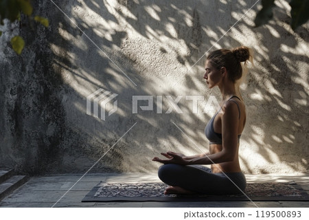 Young woman practicing yoga outdoors in the sunlight 119500893