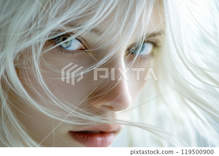 Close up of young woman with platinum blonde hair blowing in wind 119500900