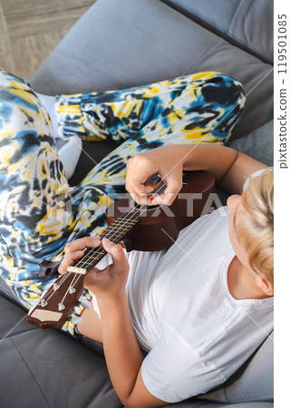 Teen boy playing ukulele, enjoying music. Teen boy playing ukulele, enjoying music. 119501085