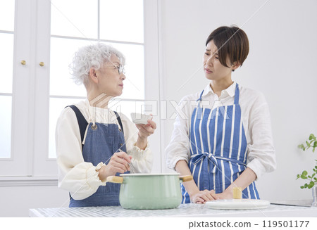 Mother-in-law checking her daughter-in-law's cooking 119501177
