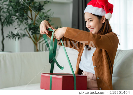 Young Asian woman wearing Christmas hat and opening a gift box 119501464