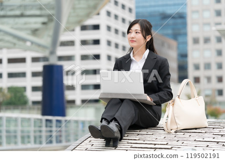 Young business woman in a suit working on a laptop outdoors Young business woman in a suit working on a laptop outdoors 119502191