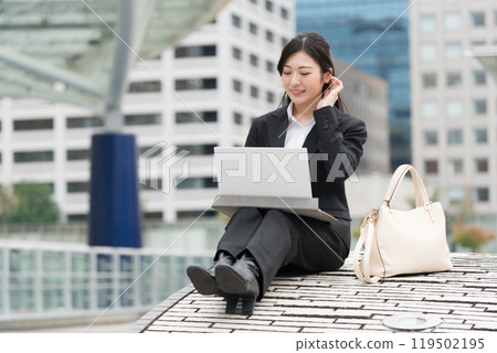 Young business woman in a suit working on a laptop outdoors Young business woman in a suit working on a laptop outdoors 119502195