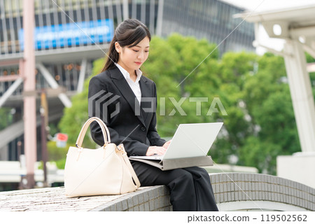 Young business woman in a suit working on a laptop outdoors 119502562