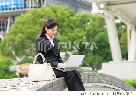 Young business woman in a suit working on a laptop outdoors 119502564