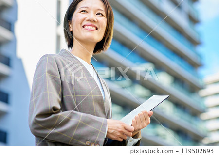 Businesswoman standing in front of an apartment building 119502693
