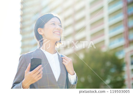 Businesswoman holding a smartphone outdoors 119503005