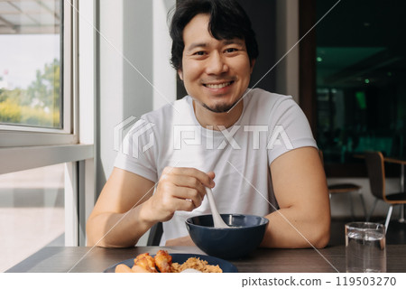 Happy man is having breakfast in the hotel dinning room. Happy man is having breakfast in the hotel dinning room. 119503270