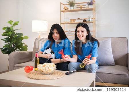Lesbian Couple Cheering for Football Together at Home, Enjoying Snacks and Drinks, Celebrating Sports Enthusiasm and Love, Cozy Living Room Setting, Happy Moments and Togetherness Lesbian Couple Cheering for Football Together at Home, Enjoying Snacks and Drinks, Celebrating Sports Enthusiasm and Love, Cozy Living Room Setting, Happy Moments and Togetherness 119503314