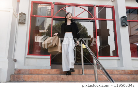 Stylish Young Woman Shopping with Multiple Bag Outside Modern Storefront on Sunny Day Stylish Young Woman Shopping with Multiple Bag Outside Modern Storefront on Sunny Day 119503342