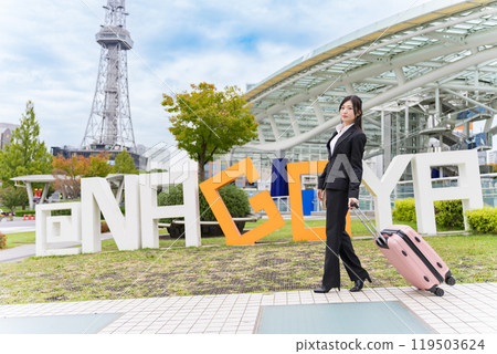 一位年輕的女商人拖著行李箱到名古屋出差 一位年輕的女商人拖著行李箱到名古屋出差 119503624
