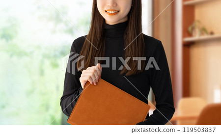 Smiling woman/businesswoman holding a binder 119503837