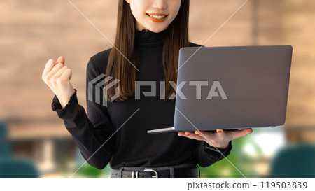 A young woman/businesswoman doing a fist pump while looking at a computer 119503839