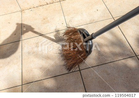 Sweeping outdoor tiles with a broom 119504017