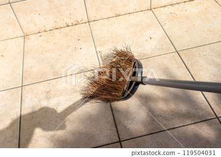 Sweep the tiled terrace with a broom 119504031