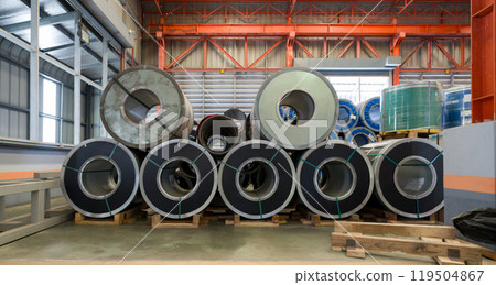 Steel coils stacked in a warehouse, ready for industrial use and distribution. 119504867