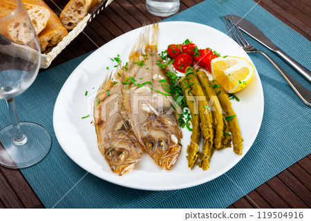 Fried roosterfish with asparagus, tomatoes and lemon 119504916