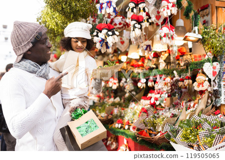 Man with girl buying Christmas decoration with tree leave at fair Man with girl buying Christmas decoration with tree leave at fair 119505065