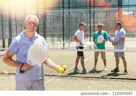 Elderly man posing on padel tennis court 119505087