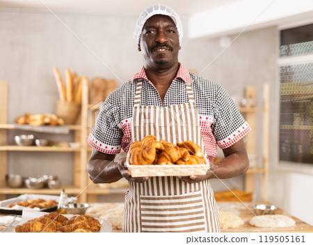 Happy male chef showing off croissants in his bakery 119505161