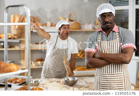In bakery kitchen, confused African male employee during quarrel with man boss In bakery kitchen, confused African male employee during quarrel with man boss 119505176