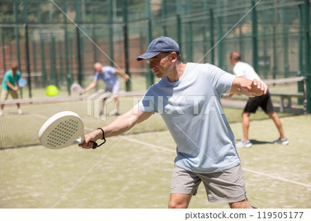 Men play padel on an outdoor tennis court. Hitting the ball with racket Men play padel on an outdoor tennis court. Hitting the ball with racket 119505177