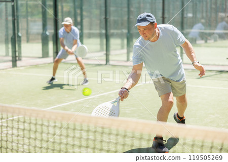 Men play padel on an outdoor tennis court. Hitting the ball with racket Men play padel on an outdoor tennis court. Hitting the ball with racket 119505269