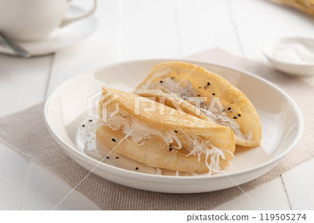 Khanom thang taek or Khanom Tang Thong, also known as poor man's pancake.Thai coconut pancake stuffed with shredded coconut and sugar sesame seed topping,a roadside snack in Thailand. Khanom thang taek or Khanom Tang Thong, also known as poor man's pancake.Thai coconut pancake stuffed with shredded coconut and sugar sesame seed topping,a roadside snack in Thailand. 119505274