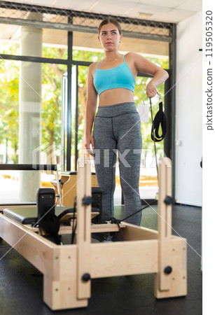 Girl stretching on pilates reformer in gym 119505320