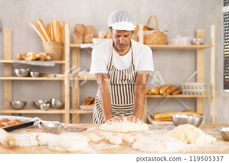 Adult male baker kneading dough on table 119505337