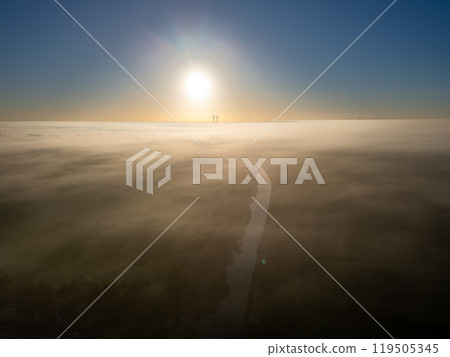 Experience the tranquility of a serene sunrise illuminating the foggy terrain with its beauty 119505345