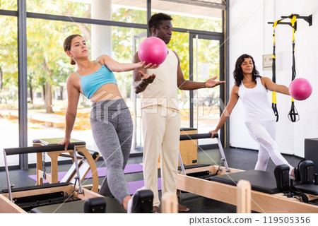 African american trainer teaches women to do pilates with pink balls 119505356