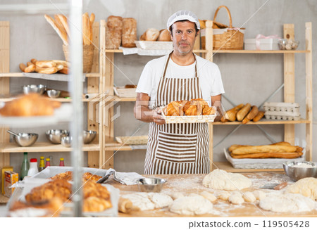 Caucasian male cook-baker worker with basket of croissant, shows many products Caucasian male cook-baker worker with basket of croissant, shows many products 119505428