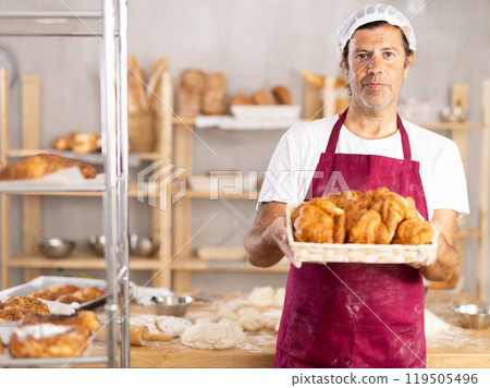Male bakery chef offers to try hot delicious croissants Male bakery chef offers to try hot delicious croissants 119505496