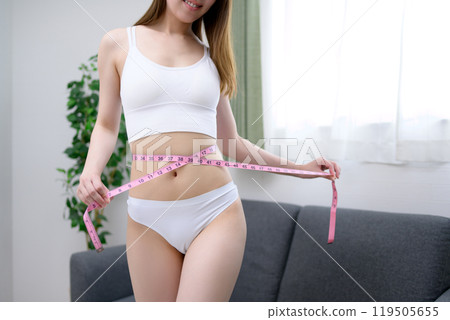 一位年輕苗條的女子用捲尺測量她的胃 — 飲食、健身、美容、運動 一位年輕苗條的女子用捲尺測量她的胃 — 飲食、健身、美容、運動 119505655