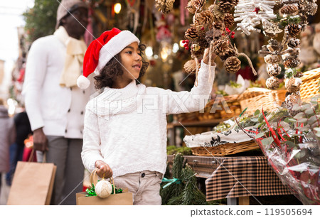 Girl with toy in hand choosing decorations at Christmas market 119505694