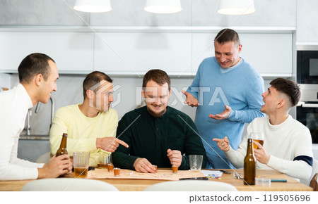 Friends drinking beer and enthusiastically playing board game at home 119505696
