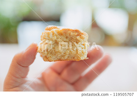 Cross section of a half-eaten scone and hand 119505707