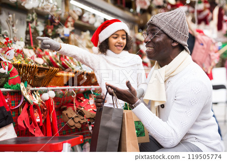 Girl with father choosing decorations and pointing to toys 119505774
